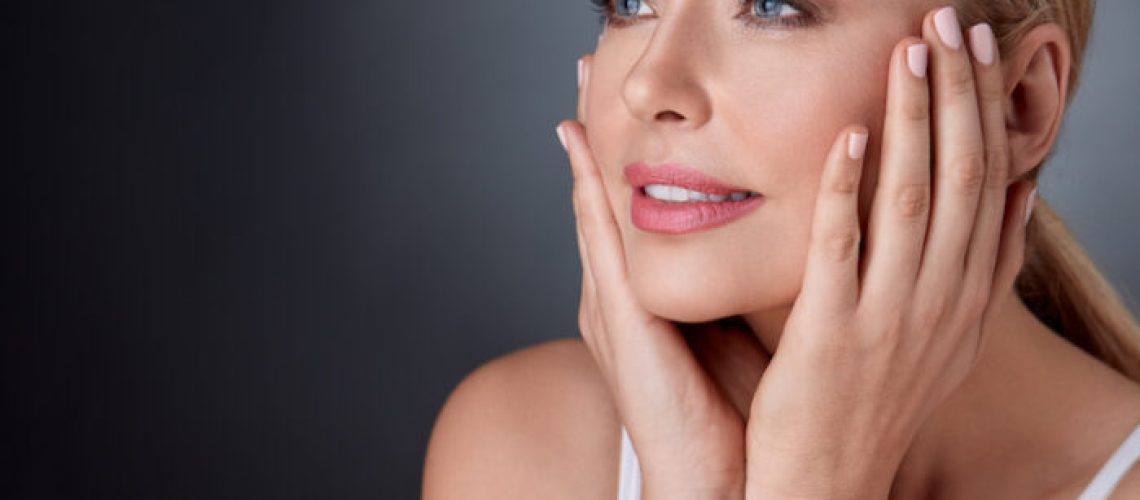 smiling woman with bare shoulders touching face